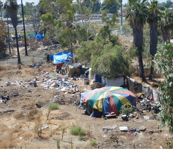 An overview of a homeless encampment filled with trash and tents.