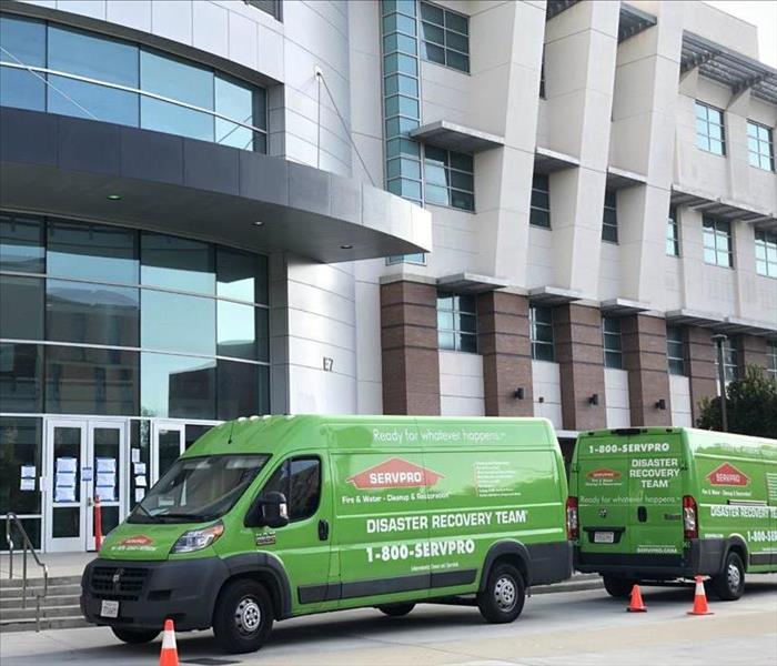 2 SERVPRO vans parked outside a large commercial building