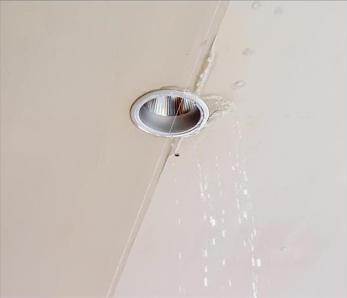 A ceiling light with signs of water damage forming around it